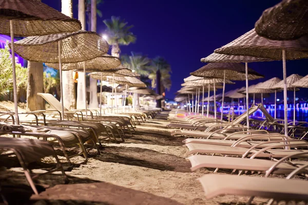 Camas de sol e guarda-sóis na praia à noite — Fotografia de Stock