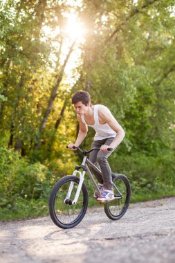 Bisikletli çocuk tavşan zıplama numarasını yapıyor.