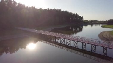 Gün batımında, ormandaki köprüyle gölün havadan görünüşü.