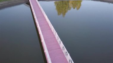 Gün batımında, ormandaki köprüyle gölün havadan görünüşü.