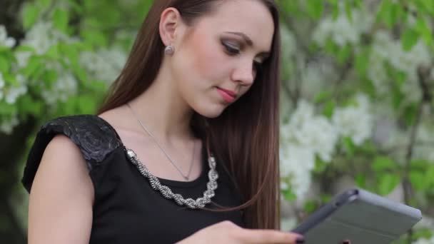 Das Mädchen mit dem digitalen Tablet im Garten — Stockvideo