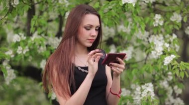 Bahçede elinde bir akıllı telefon ile kız