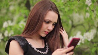 Bahçede elinde bir akıllı telefon ile kız