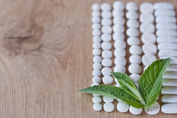 Different white pills and foliage mint — Stock Photo, Image