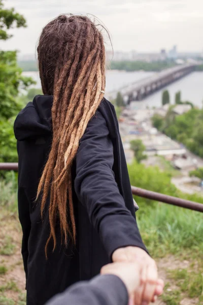 Der Typ, der Mädchen mit Dreadlocks in schwarzer Hand auf einem Hintergrund der Stadt Kyiw hält — Stockfoto