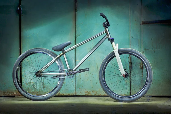 Silver bicycle on a green garage background — Stok fotoğraf