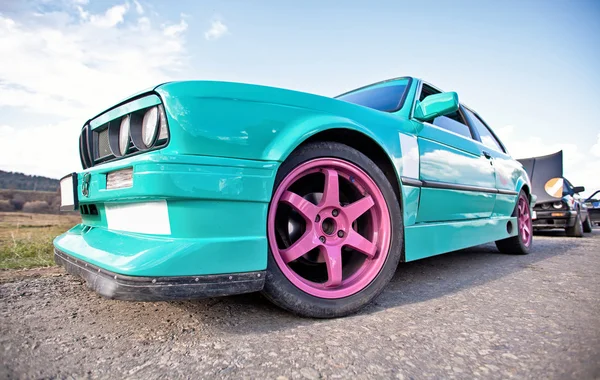 Alter grüner Sportwagen mit rosa Rädern — Stockfoto
