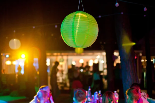 Green paper lantern outdoor party with people on background — Stock Photo, Image