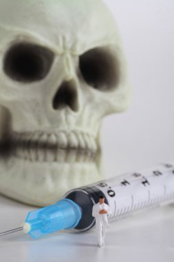 insan kafatası, minyatür bir doktor ve şırınga 