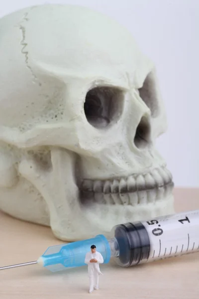Lidská lebka, miniaturní lékaře a stříkačku — Stock fotografie