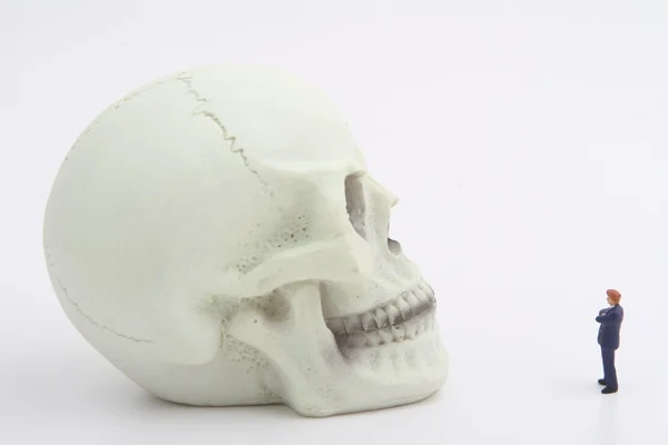 Estatueta miniatura de um homem de negócios com um crânio humano — Fotografia de Stock