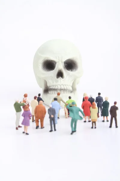 Miniature figurines crowd of people and skull — Stock Photo, Image