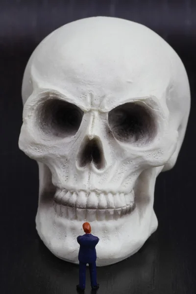 Miniature figurine of a businessman with an human skull — Stock Photo, Image