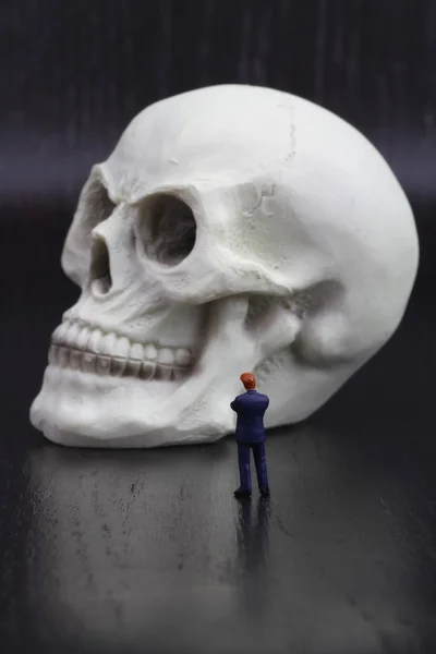 Figurine miniature d'un homme d'affaires avec un crâne humain — Photo