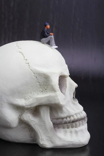 Miniature figurines of depressed people sitting on a skull — Stock Photo, Image