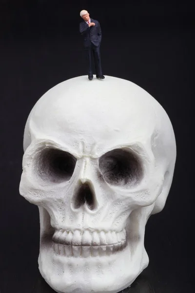 Figurine miniature d'un homme d'affaires avec un crâne humain — Photo