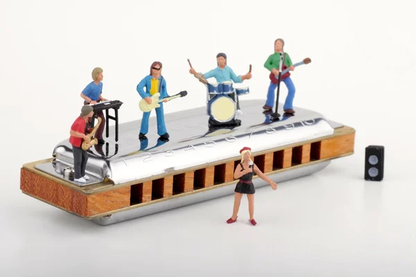 Miniatuur van een rockband uitvoeren op een grote mondharmonica — Stockfoto