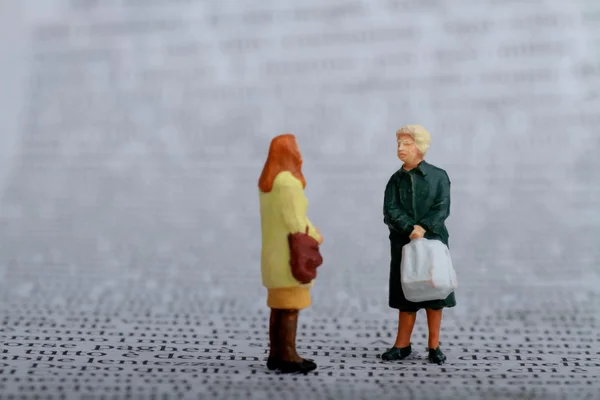 Miniature di donne che spettegolano su un giornale — Foto Stock