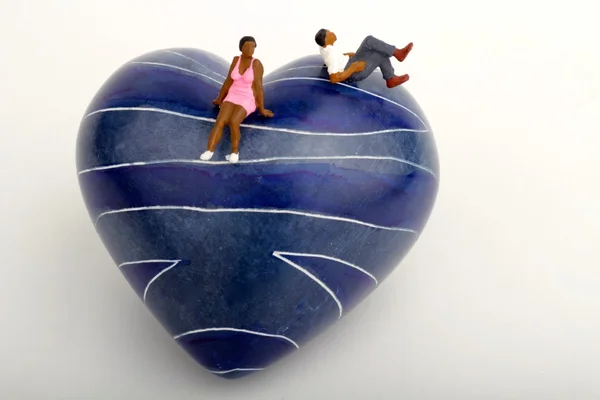 Miniature of a black couple sitting on a blue stone heart — Stock Photo, Image