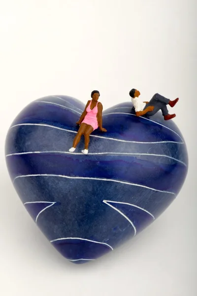 Miniature of a black couple sitting on a blue stone heart — Stock Photo, Image
