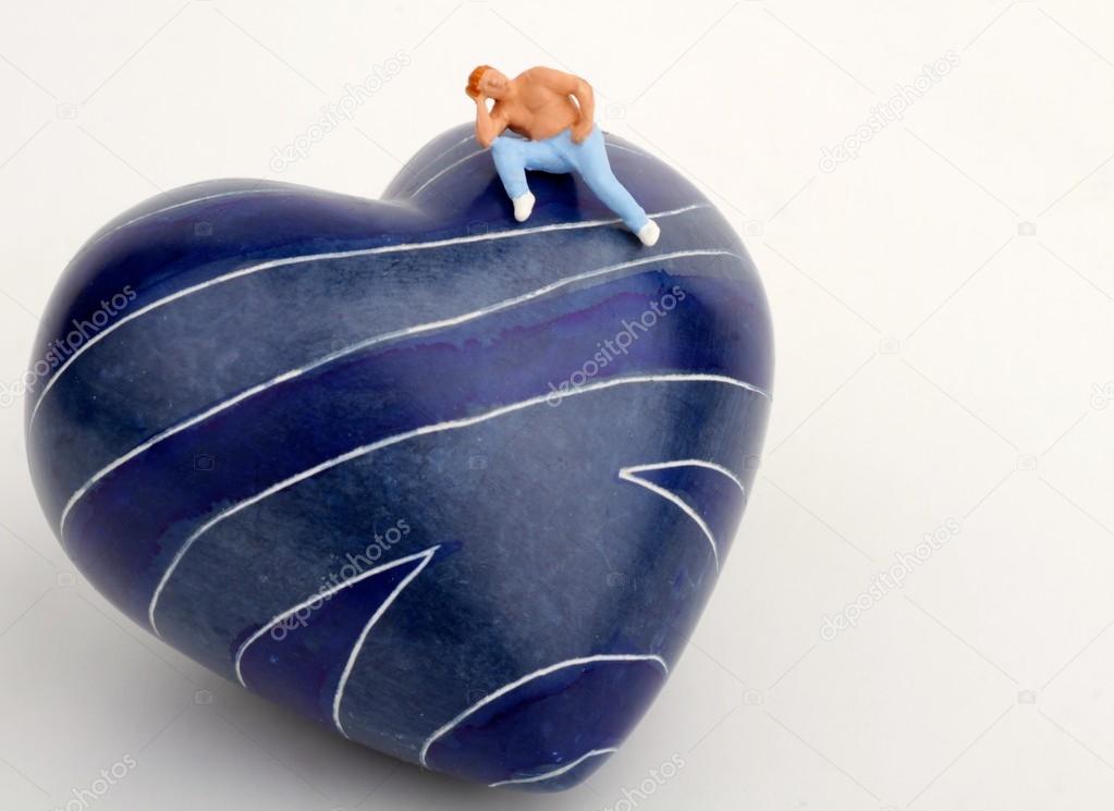 Miniature of a lonely man sitting on the top of an heart-shaped stone