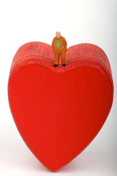 Miniature of a lonely man with business suit standing over a red heart — Stock Photo, Image