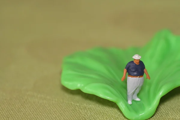 Miniature d'un homme gras et d'une feuille de salade - concept d'alimentation saine — Photo