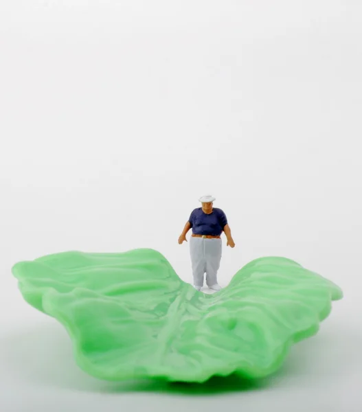 Miniatuur van een dikke man en een salade leaf - gezonde voeding concept — Stockfoto