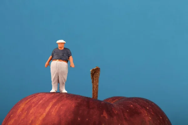 Gros homme sur le dessus d'une pomme rouge - concept d'obésité — Photo