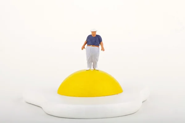 Miniature of a fat man near by a fried egg — Stock Photo, Image