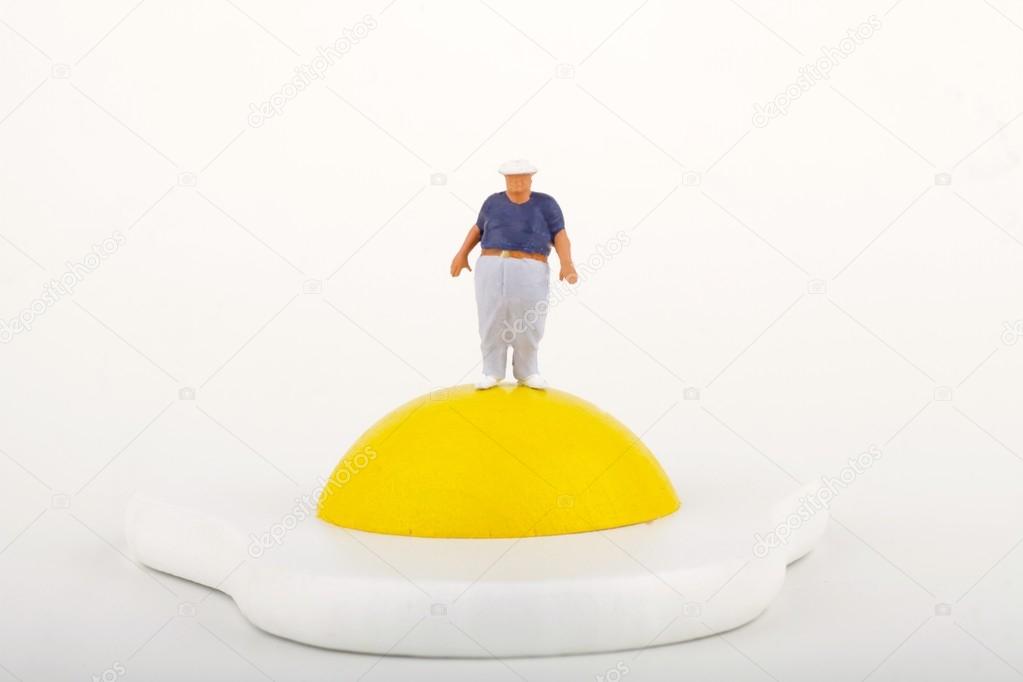 Miniature of a fat man near by a fried egg