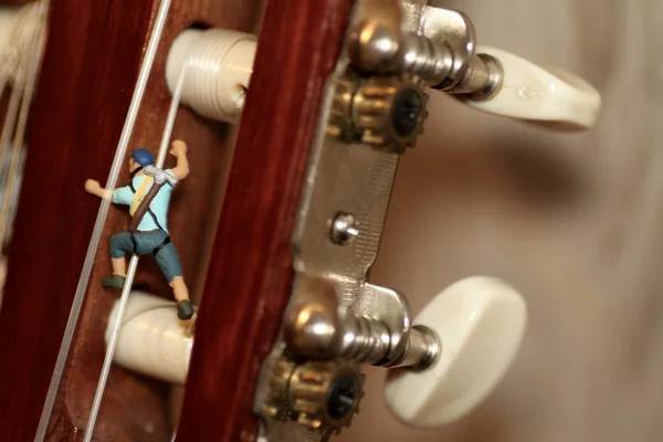 Escalador en miniatura en acción sobre una guitarra clásica —  Fotos de Stock