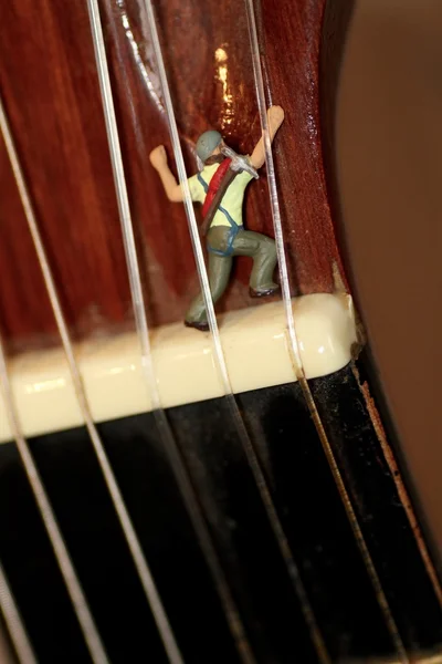 Escalador em miniatura em ação em uma guitarra clássica — Fotografia de Stock