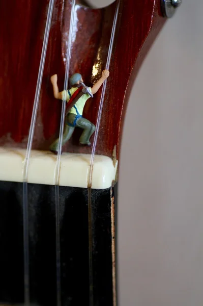 Escalador en miniatura en acción sobre una guitarra clásica — Foto de Stock