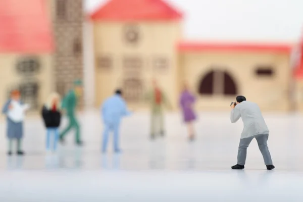 Miniature of a street photographer taking pictures of strangers walking on ta white background — Stock Photo, Image