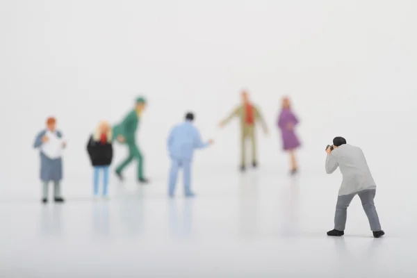 Miniatuur van een straat fotograaf nemen van foto's van vreemden lopen op ta witte achtergrond — Stockfoto