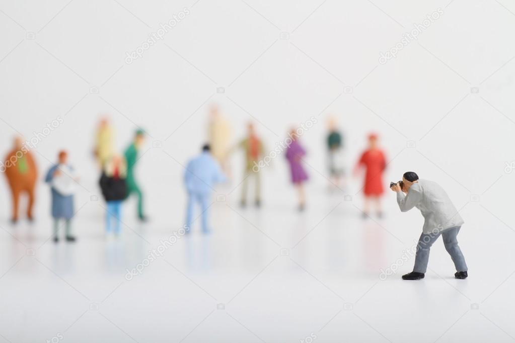 Miniature of a street photographer taking pictures of strangers walking on ta white background