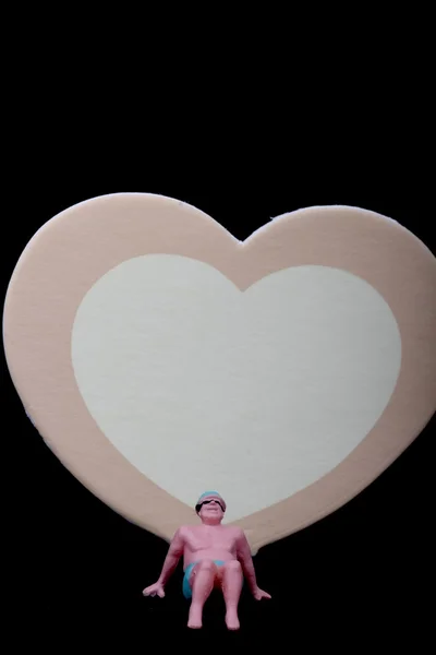 Minyatür bir kalp altında oturan bir mayo ile yalnız bir adamın — Stok fotoğraf