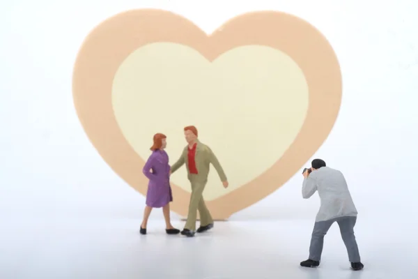 Мініатюра фотографа, який фотографує молоду пару з рожевим і жовтим серцем як фон — стокове фото