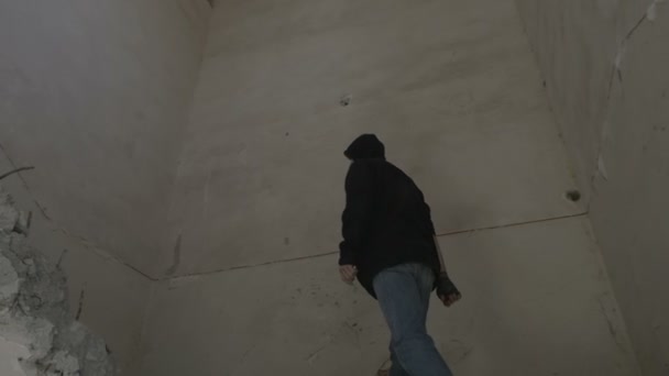 Jeune homme à capuchon montant les escaliers d'un bâtiment abandonné 