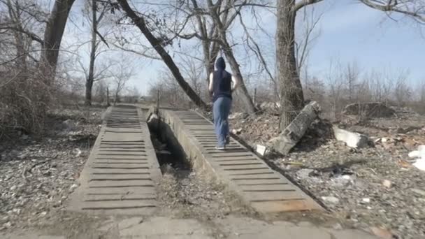 Молодой человек в капюшоне бегает в заброшенном месте — стоковое видео