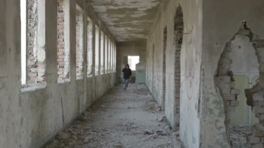 Terk edilmiş bir askeri binada çalışan kukuletalı korkmuş genç adam