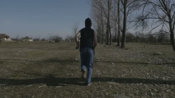Fiatal csuklyás férfi egy elhagyatott helyen jogging — Stock videók