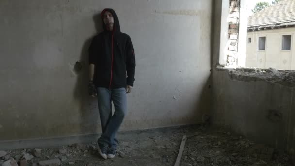 Hooded depressed young man sitting in an abandoned building — Stock Video