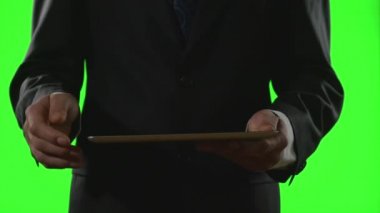 Genç işadamı yeşil ekran üzerinde bir sanal iş ortamında bir tablet PC'yi kullanma