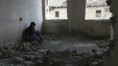 Terk edilmiş bir binada oturan kukuletalı depresif genç adam