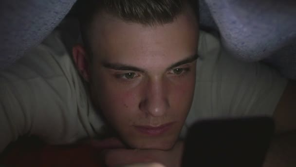 Attractive young man using a smart phone in bed — Stock Video