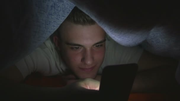 Aantrekkelijke jonge man browsen van social media op een slimme telefoon in bed — Stockvideo