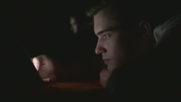 Jeune homme attrayant utilisant un téléphone intelligent au lit 