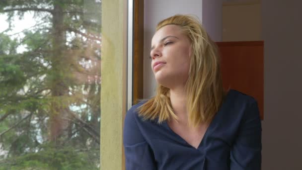 Νεαρή γυναίκα λυπημένος ψάχνει έξω από το παράθυρο και να περιμένει — Αρχείο Βίντεο